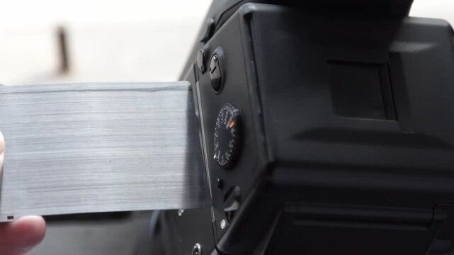 Photographer inserting film holder into medium format camera