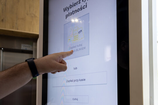 Poznan, Poland - June 18, 2025: BLIK payment method displayed on a self-service kiosk screen, a person's hand choosing the digital transaction for fast convenience