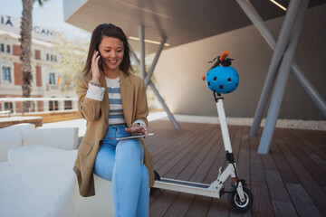 Asian woman with e scooter in town near business quart