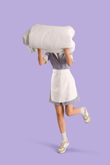 Female housekeeper with white folded blanket on lilac background