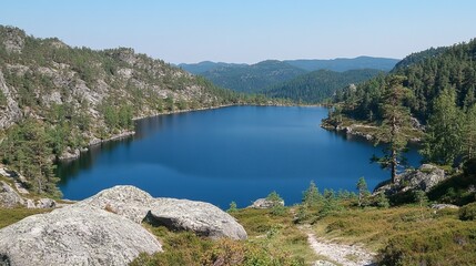Obraz premium Serene mountain lake nestled amidst rocky terrain, showcasing deep blue waters and lush greenery under a clear sky
