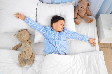 Cute little boy with teddy bear sleeping in bedroom
