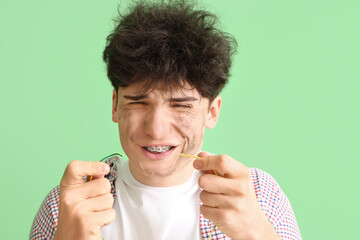 Electrocuted young man with burnt face and wire on green background, closeup