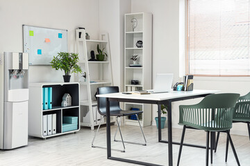 Interior of light office with modern water cooler near white wall