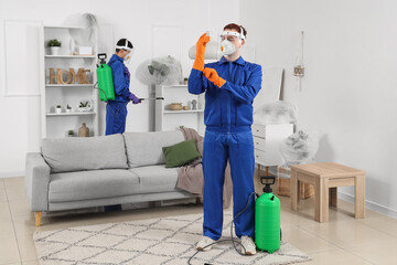 Male workers in protective suits disinfecting room