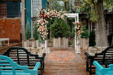 Elegant outdoor wedding ceremony venue with floral arch and rug in rustic garden setting