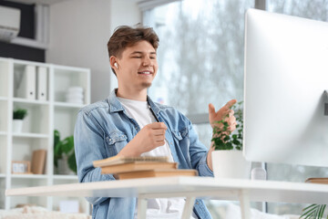 Male student in earphones studying online at home