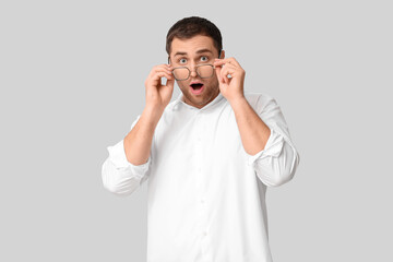 Shocked young man in eyeglasses on white background