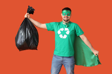 Young man dressed as eco superhero with garbage bag on orange background. Ecology concept