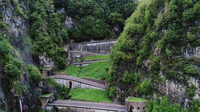 Curving alpine road cuts through steep cliffs of San Boldo Pass under cloudy sky