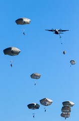 Military parachutist paratroopers parachute jumping out of an air force plane.