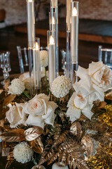 Elegant white rose and gold floral centerpiece with tall candles for luxurious table setting
