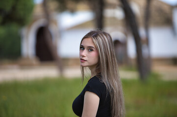 portrait of young and beautiful blonde woman, wearing jeans, black shirt walking in the countryside...