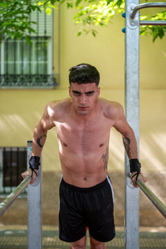Young man performing calisthenics dips on parallel bars outdoors