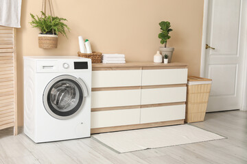 Interior of home laundry room with modern washing machine, dresser and basket
