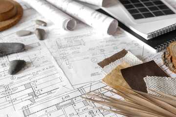 sustainable architecture tools and materials: blueprints, solar panel, wood textures, fabric swatches, and stones. Eco-friendly design, conscious construction and green innovation.