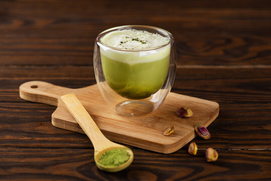 Pistachio green matcha latte tea with whipped milk in a glass on a wooden board. - Powered by Adobe