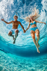 Young man and woman jumping into water. Shot on fish-eye camera. Vertical layout. Immersive POV