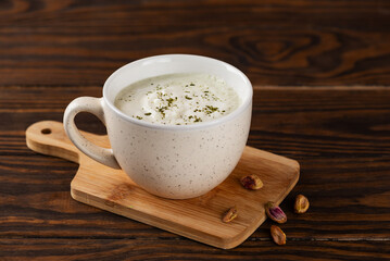 Pistachio green tea latte, Japanese matcha latte, with whipped green tea and milk on a wooden board.