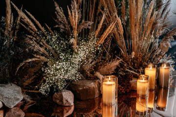 Warm candlelight amongst dried flower arrangement with pampas grass and rocks