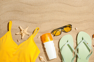 Summer composition with swimsuit and beach accessories on sand as background, closeup