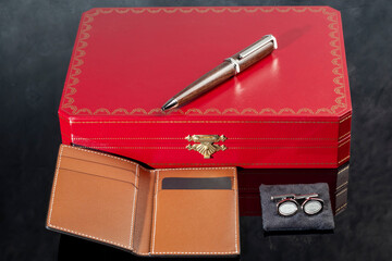 Branded pen with cufflinks and business card holder in a box. Gift set. Office interior.