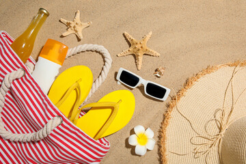 Composition with bottle of sunscreen cream, starfishes and beach accessories on sand as background,...