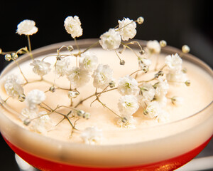 blush-toned cocktail with a frothy top is elegantly garnished with delicate white baby's breath...