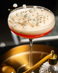 blush-toned cocktail with a frothy top is elegantly garnished with delicate white baby's breath...