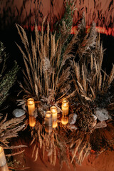 Calming candlelit dried pampas grass and pebble arrangement with reflective water