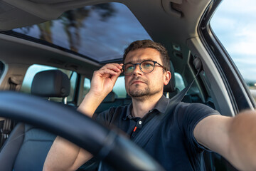 Man driving car. Adjusting glasses gesture. Focused driving.