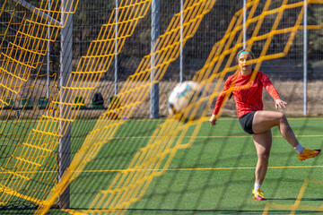Sporty girl scores a goal into the goal. Football concept. Girl on the football field.