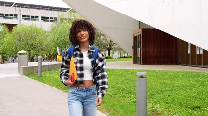 Confident african american female student walking with purpose across modern university campus, carrying backpack and embodying academic ambition and future potential