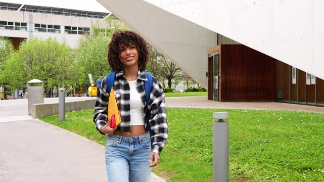 Confident african american female student walking with purpose across modern university campus, carrying backpack and embodying academic ambition and future potential - Powered by Adobe