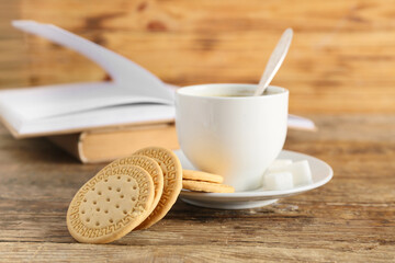 Sweet cookies and cup of hot coffee on wooden background