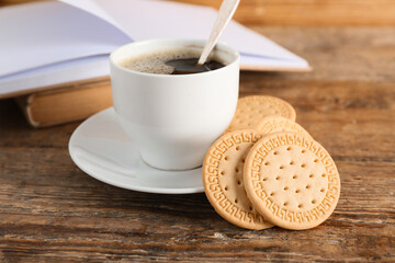Sweet cookies and cup of hot coffee on wooden background