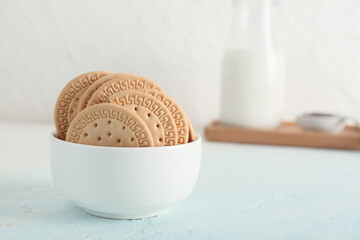 Bowl with sweet cookies on light blue background
