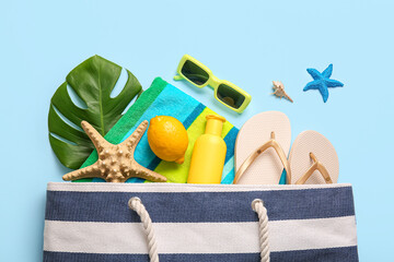 Summer composition with lemon, green leaf and beach accessories on blue background