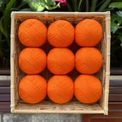 Nine orange yarn balls in a basket, outdoors. Craft supplies for knitting or crochet