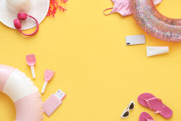 Frame made of inflatable rings, mobile phone and beach accessories on yellow background