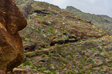 Volcanic trail under rugged cliff