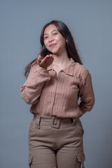 A cheerful Indonesian woman blowing a kiss with a playful smile. Her body language and facial...