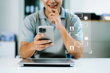 Man holds smartphone over laptop with chat bubbles overlay, illustrating modern digital messaging,...