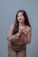 Portrait of a young Indonesian woman with long hair smiling softly, leaning slightly forward with...