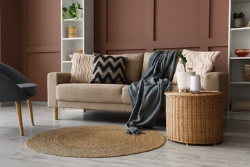 Interior of living room with comfortable sofa and table near brown wall, closeup