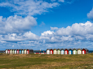 Multi-coloured beach huts at Blyth, Northumberland, UK with lighthouse and copy space
