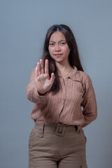 Indonesian woman in beige shirt, holding her hand up in a 