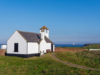 Watch House Museum on Rocky Island, Seaton Sluice, Northumberland, UK with St Mary's Island and lighthouse in the background.