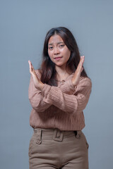An Indonesian woman with long hair, wearing a beige blouse and khaki pants, demonstrates a body...