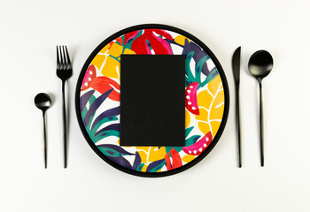 Top view of black tray, colorful plate, black cutlery on white background. Black card, exotic plant plate, summer picnic. Flat lay, copy space.